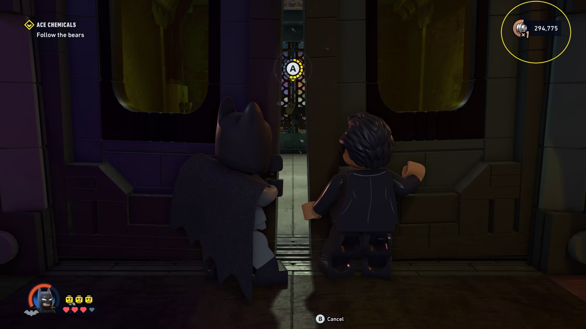 In 'LEGO Batman: Legacy of the Dark Knight', Batman and another character peek through a partially opened door in the 'Ace Chemicals' level with an objective to 'Follow the bears.'