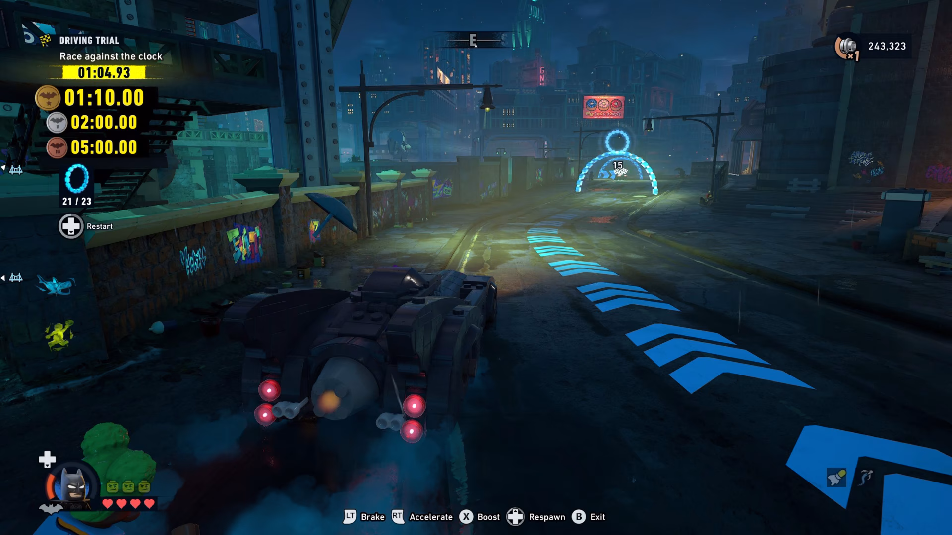 In the game LEGO DC Super-Villains, a player, controlling LEGO Batman in a Batmobile, is racing against the clock showing a time of '01:04.93' on a street with highlighted arrows, aiming to pass through a glowing ring ahead.